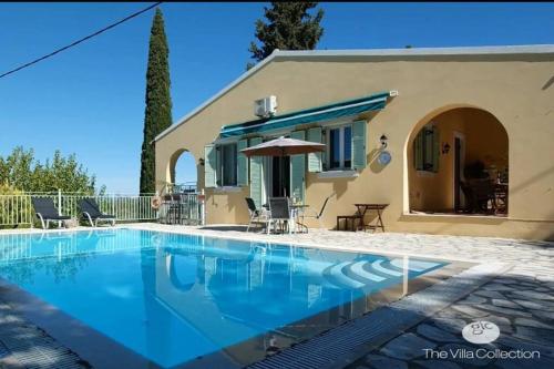 a villa with a swimming pool in front of a house at Gastouri Villa Pascalia with heated pool in October and views in Achílleion