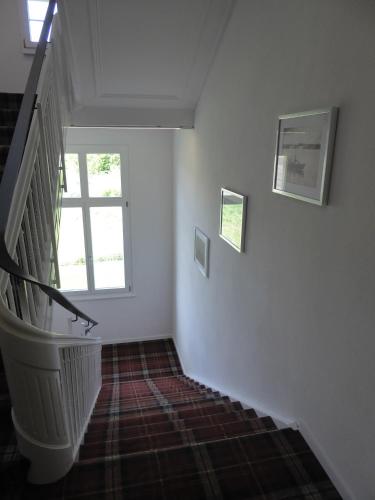 a hallway with a staircase with two windows and a stair case at VILLA TAEGERMOOS in Tägerwilen