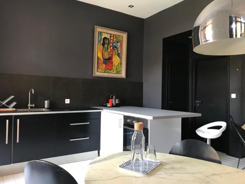 a kitchen with black cabinets and a table with a bottle of wine at Un soir d'été - Chambres d'hôtes in Ernolsheim-Bruche