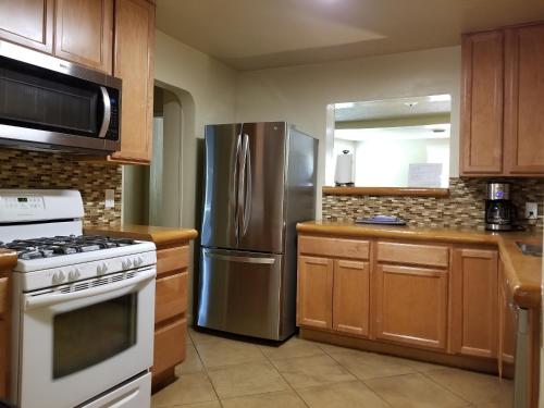 a kitchen with a stainless steel refrigerator and wooden cabinets at Quiet Desert Oasis off Swan Rd in Tucson