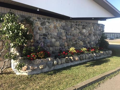 a stone retaining wall with flowers in a garden at Motel La Marina in Matane