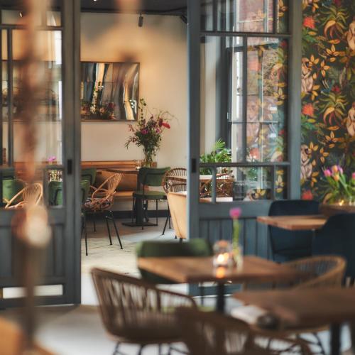 a restaurant with tables and chairs and a wall of windows at Dorpsherberg De Roskam in Nunspeet