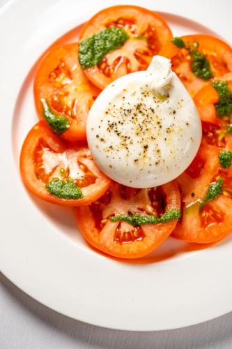 a plate of food with an egg on top of tomatoes at Capital Plaza Hotel in Bucharest