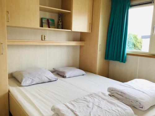 1 cama con 2 almohadas en una habitación con ventana en Chalet Kocky, en Midsland