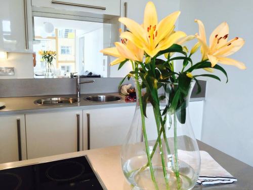 a vase filled with yellow flowers on a kitchen counter at Manchester City Centre Modern 3bed 2bath Apartment PENTHOUSE Northern Quarter, Sleeps 10 in Manchester