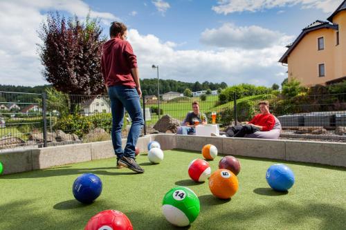 a man is playing with balls on the grass at Appartementhaus EifelAdventures in Berlingen