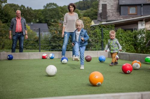 a woman and two children playing with balls on a lawn at Appartementhaus EifelAdventures in Berlingen