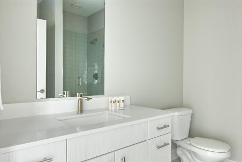 La salle de bains blanche est pourvue d'un lavabo et de toilettes. dans l'établissement Sonder Belcourt, à Nashville