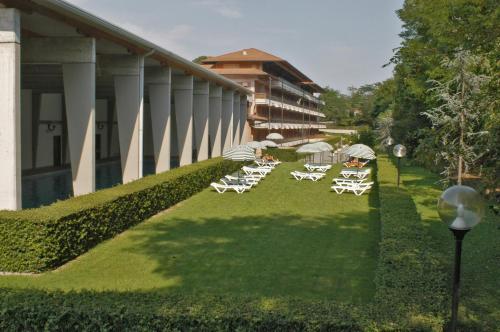 a group of lounge chairs and umbrellas on a lawn at Residence Hotel Health House in Desenzano del Garda