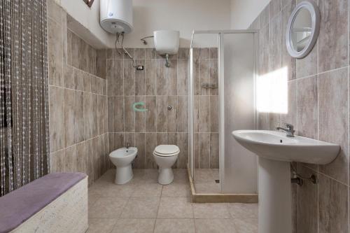 e bagno con servizi igienici, lavandino e doccia. di Villa Nataly by BarbarHouse a Torre Chianca