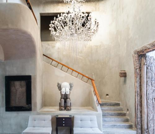 a chandelier in a room with a staircase with white stools at Casa Malca in Tulum