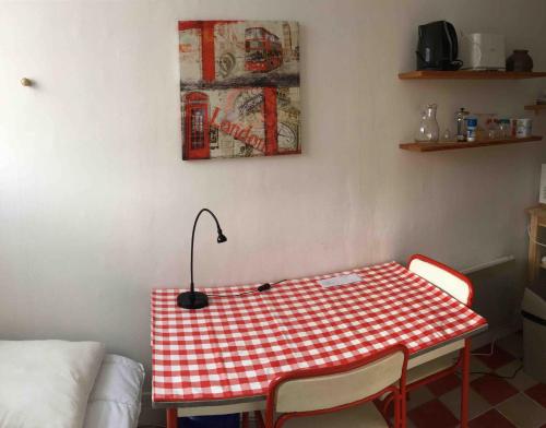 une table à damiers rouge et blanc avec des chaises et une lampe dans l'établissement Studio Picnic, à Chambéry