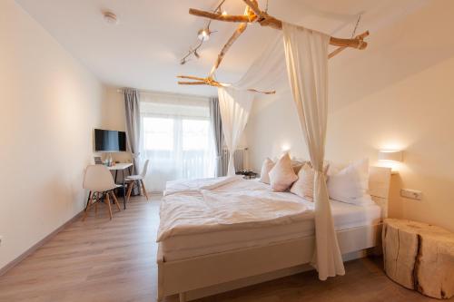 1 dormitorio con 1 cama con dosel en Appartementhaus EifelAdventures, en Berlingen