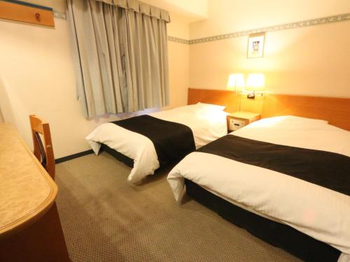 福井市にあるアパホテル福井片町のベッド2台とテーブルが備わるホテルルームです。
