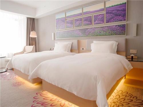 Un dormitorio con dos camas y un cuadro en la pared. en Lavande Hotel Jinan High-Tech Wanda Exhibition Center, en Jinan