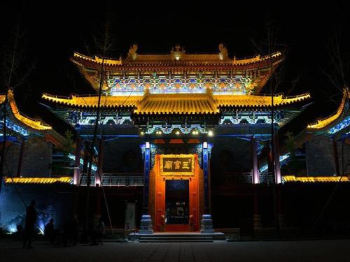 an asian building with a gate at night at 7Days Inn Qingzhou Pingzhangfu Store in Weifang