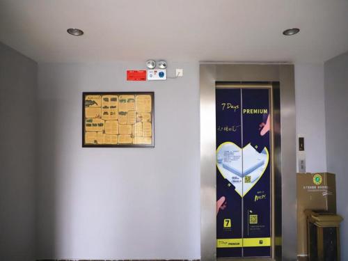 a elevator in a building with a sign on the wall at 7Days Inn Qingzhou Pingzhangfu Store in Weifang