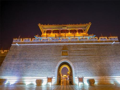 a large brick building with an arch at night at 7Days Inn Qingzhou Pingzhangfu Store in Weifang