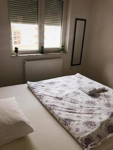 a bed with a blanket on it in a room with two windows at Blini Complex in Pristina