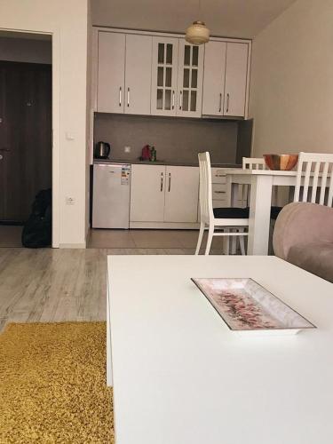 a living room with a table and a kitchen with white cabinets at Blini Complex in Pristina