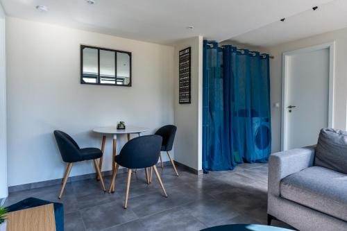 un salon avec une table, des chaises et un canapé dans l'établissement Le 21 -GregIMMO-Appart'Hôtel, à Montbéliard