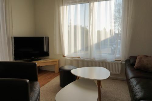 a living room with a couch and a table and a tv at Modern chalet at holiday park in Opmeer near Amsterdam in Opmeer