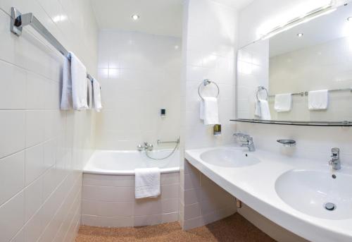 a white bathroom with a sink and a mirror at Hotel Karl Schranz in Sankt Anton am Arlberg