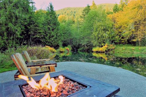 a fire pit with a bench next to a lake at Alexander's Lodge in Ashford