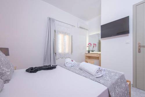 a white bedroom with a bed and a television at Santorini 180 Degrees in Pyrgos