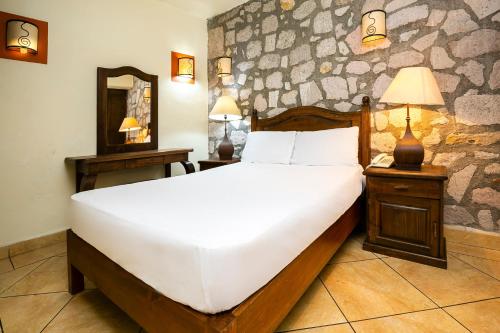 Hotel Casa del Virrey & Suites في موريليا: غرفة نوم بسرير ابيض كبير ومرآة