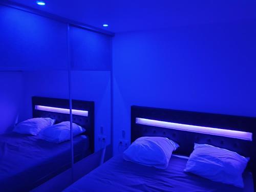 Le Cap d'Agde NATURISTE Grand T2 de standing avec GARAGE في كاب داغد: سريرين في غرفة ذات إضاءة زرقاء