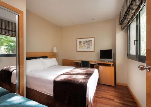 バリャドリッドにあるHotel Ciudad de Valladolidのベッドとテレビが備わるホテルルームです。