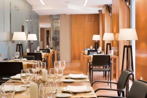 a restaurant with long tables and chairs and lamps at NH Zamora Palacio del Duero in Zamora