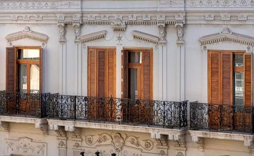 a white building with brown shutters and a balcony at NH Collection Colón Valencia in Valencia