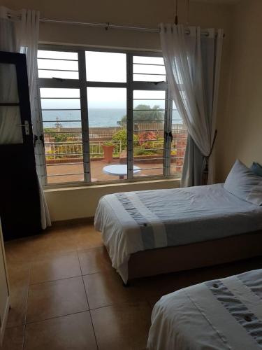 a bedroom with two beds and a large window at 3 Marilyn Court in Scottburgh