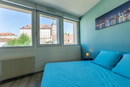 a bedroom with a blue bed and two windows at Le 15-GregIMMO-Appart'Hôtel in Montbéliard