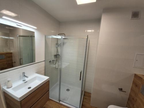 łazienka z przeszkloną kabiną prysznicową i umywalką w obiekcie Apartament 15 w Świnoujściu