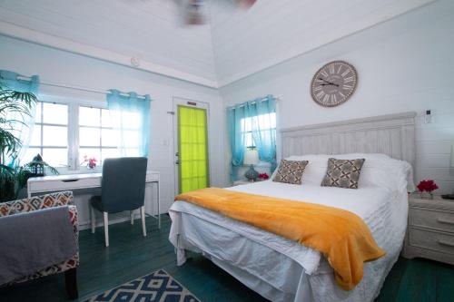 ein Schlafzimmer mit einem Bett, einem Schreibtisch und einer Uhr in der Unterkunft Garden Cottage - At Orange Hill in Nassau