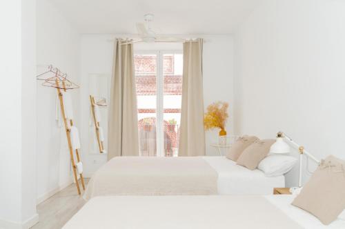 a white bedroom with two beds and a window at Dulces Dreams Boutique Hotel in Málaga