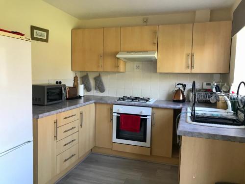 a kitchen with wooden cabinets and a stove top oven at Kettering Leisure Holiday Home in Kettering