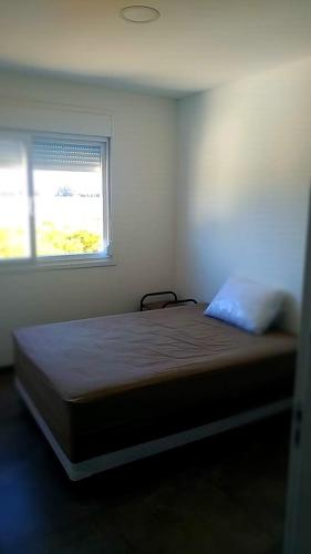 um quarto com uma cama e uma janela em CASA EM CONDOMÍNIO - 3 dormitórios - LAZER COMPLETO - Xangri-lá em Xangri-lá