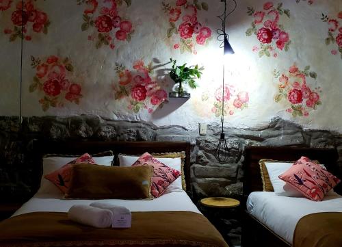 a bedroom with two beds with flowers on the wall at Niños Hotel Meloc in Cusco