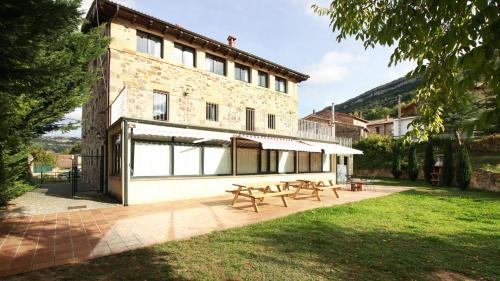 un edificio con dos mesas de picnic delante de él en La Romanika de Fellini, en San Martín de Elines