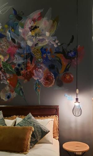 a bedroom with a painting of flowers on the wall at Niños Hotel Meloc in Cusco