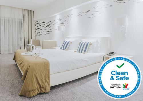 a white bedroom with a large white bed with birds on the wall at MH Peniche in Peniche