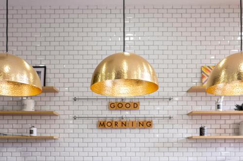 three gold pendant lights hanging from a white brick wall at Holiday Inn Madrid - Las Tablas by IHG in Madrid