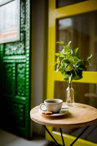 a table with a cup and a vase with a plant at Niños Hotel Meloc in Cusco