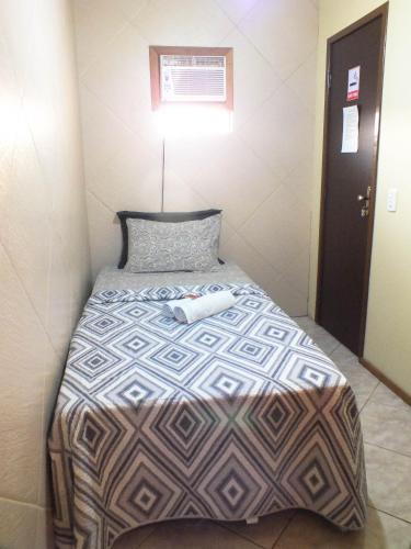 a bed in a small room with a white towel on it at Aeropouso Pousada Executiva in Florianópolis