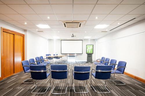 a conference room with chairs and a projector screen at Holiday Inn Coventry M6, J2 by IHG in Coventry