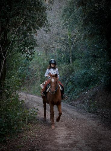 a young girl riding a horse down a dirt road at Can Congost in Sort
